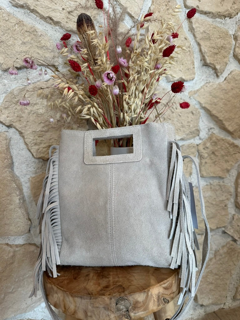 Petit sac en cuir beige à franges posé sur tabouret